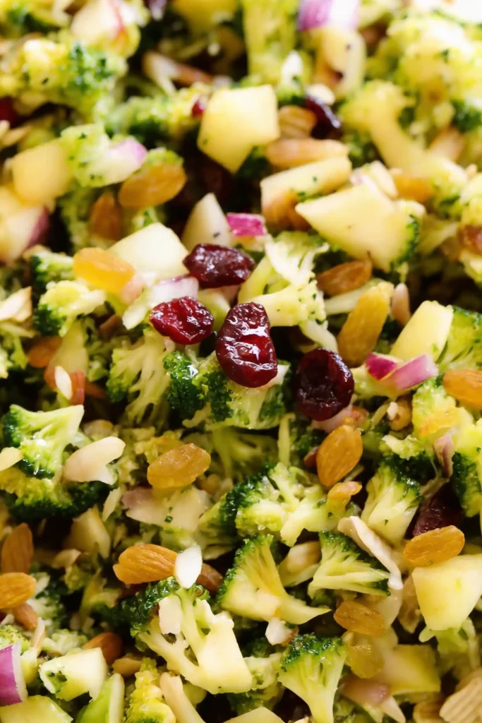 Close-up of Broccoli Salad with broccoli florets, apples, almonds, dried cranberries, and red onions, highlighting fresh and healthy ingredients