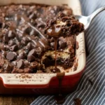 Fluffy Cottage Cheese Microwave Brownie with powdered sugar and almond slices, served on a red-and-white baking dish over a wooden surface