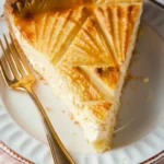 Slice of Italian Ricotta Pie with golden patterned crust and creamy filling on a white plate with a gold fork