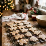 Iced gingerbread cookies shaped like men, stars and trees on a cooling rack with Christmas lights behind